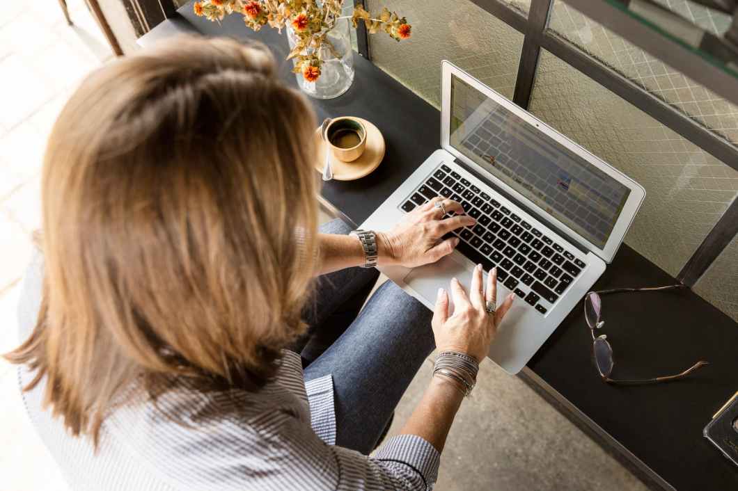 person sitting while typing on gray laptop